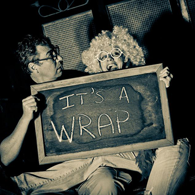 Two people at a party with a sign saying it's a wrap.
