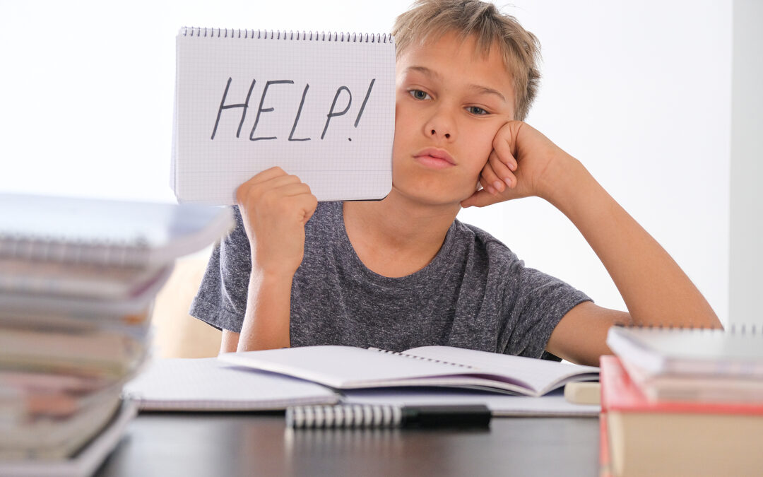 Pre-teen sitting at a desk taking a dyslexia test and holding up a written sign that says help.